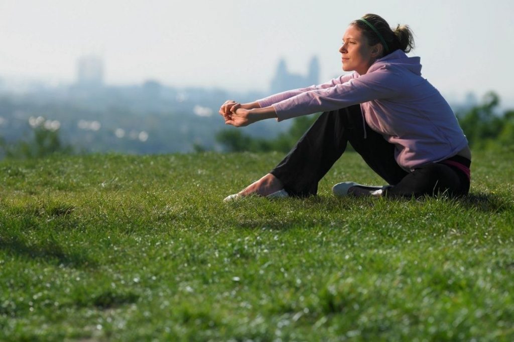 woman sits in grass taking time for self kindness