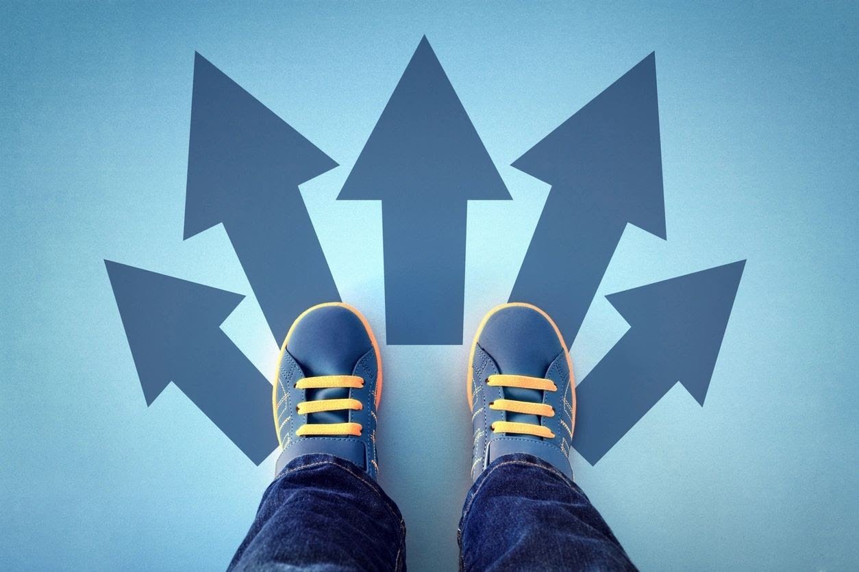 a young boys feet are positioned behind five arrows on the ground like not knowing which way to go trying to decide is homeschooling better than distance learning