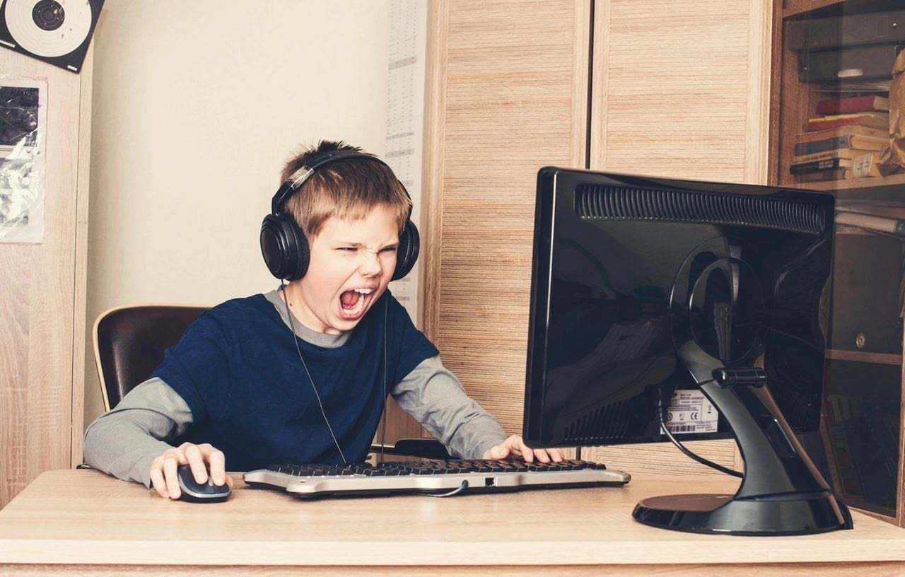 a young boy screams at a computer screen looking frustrated or angry
