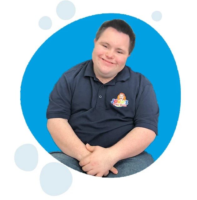 john sits and smiles at the camera wearing a navy blue johns crazy socks pullover for his business that employs adults with differing abilities