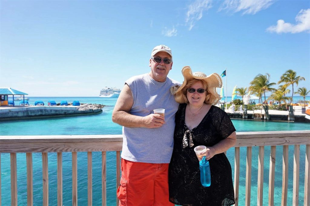 man and woman standing on a bridge overlooking the Caribbean sea with a cruise ship in the background