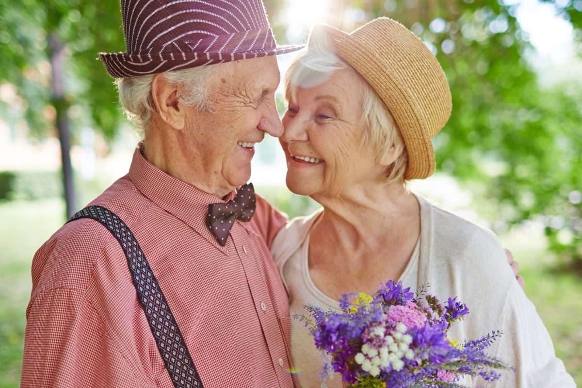 elderly couple hugging in a garden looking lovingly into each others eyes