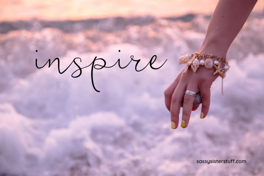 female hand with ocean charm bracelet on a cloud background with inspirational quotes