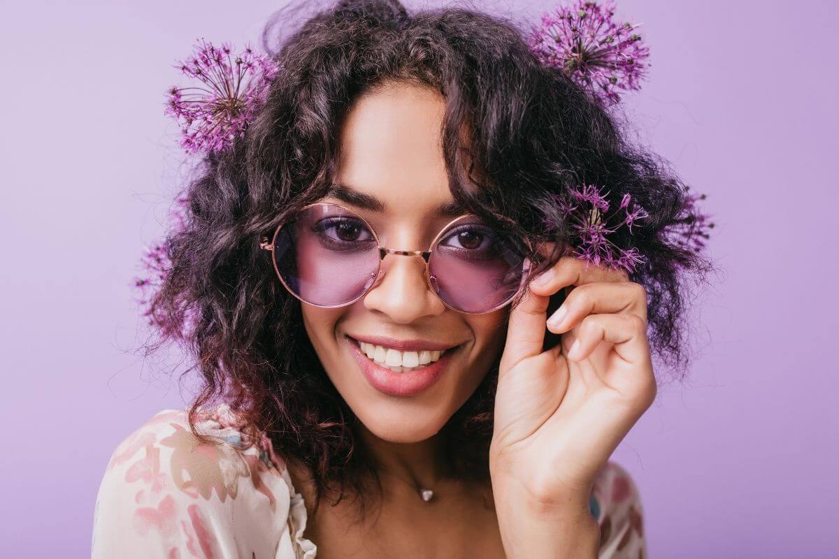 happy young women with purple flowers in her haid and purple sunglasses and a lavender background