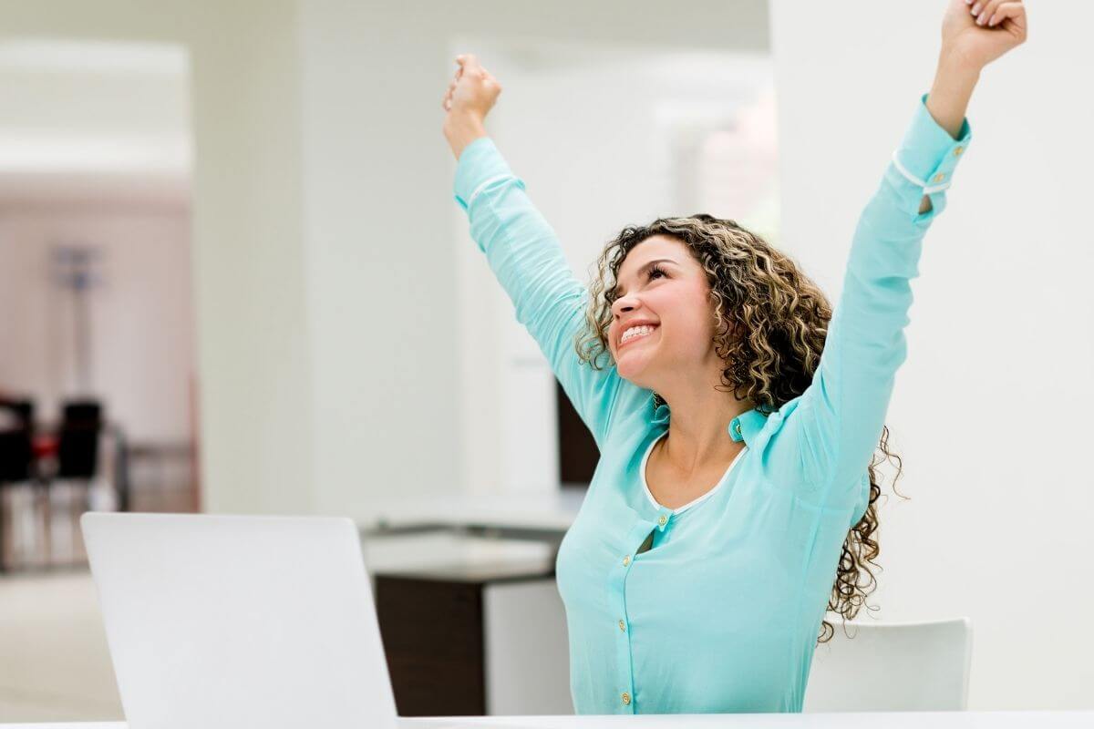 young woman reaching into the air with a beautiful smile on her face to celebrate life every day