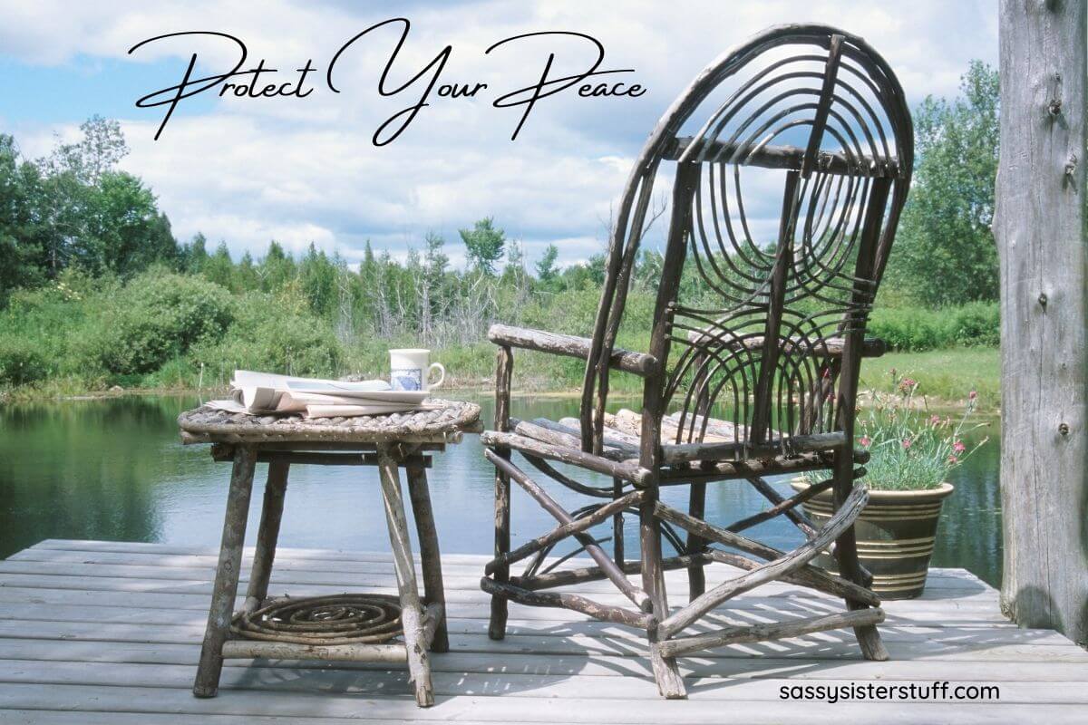 wooden chair and small table sitting on a deck looking over a pond with woods in a very peaceful setting