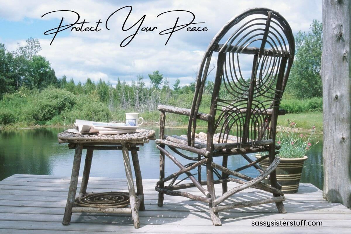 wooden chair and small table sitting on a deck looking over a pond with woods in a very peaceful setting