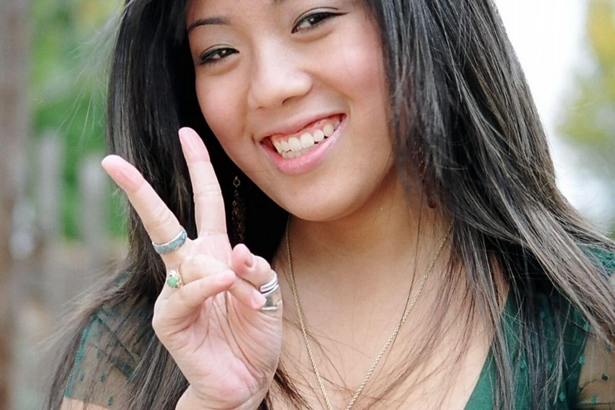 happy woman holds up two fingers for a peace sign