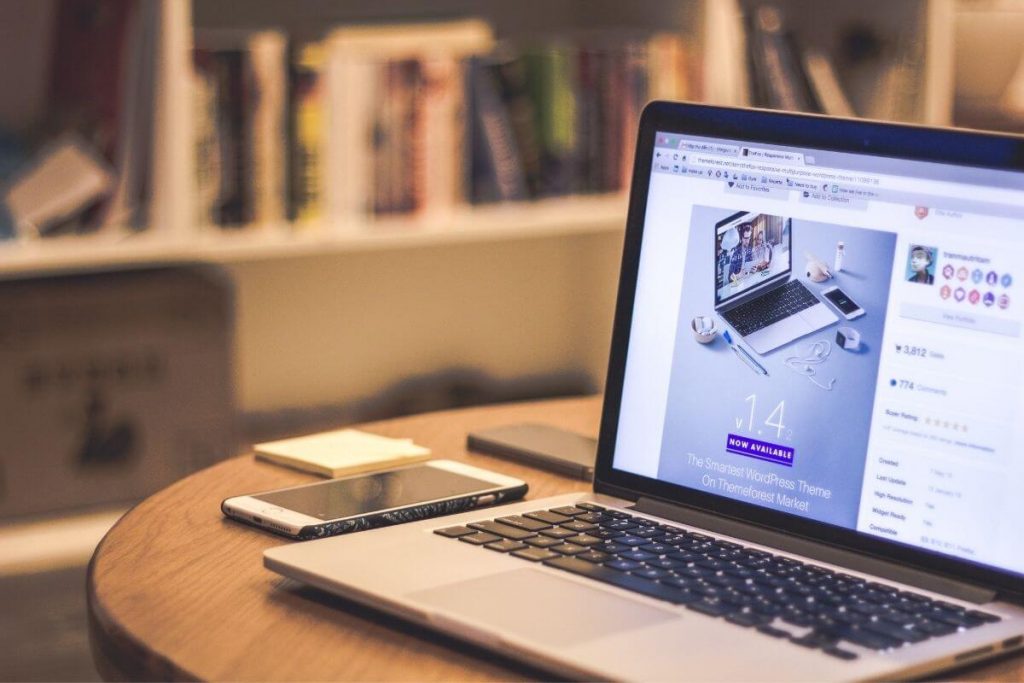 open laptop with wordpress design on it and bookshelves in the background
