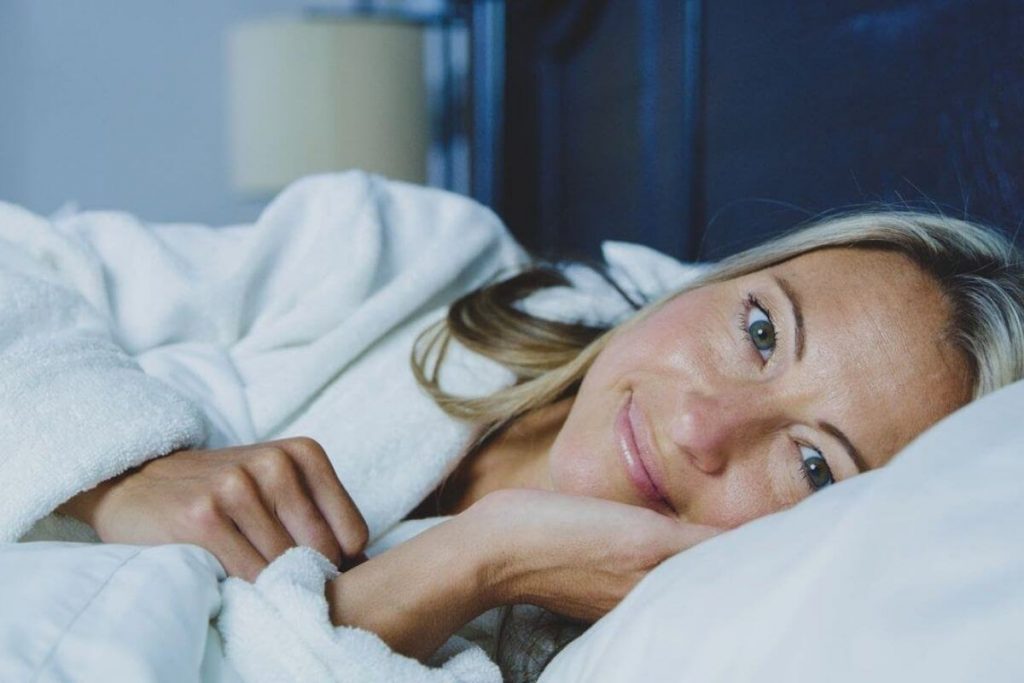 sleep hygiene | sleep strategies a women snuggles in bed resting for good health