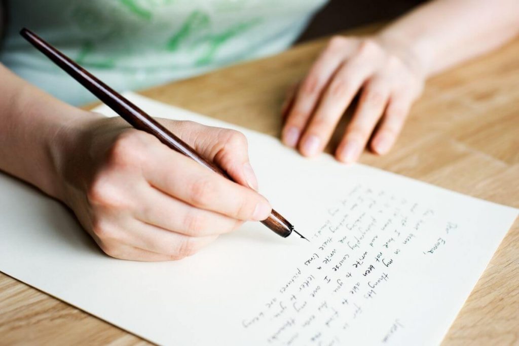 someone writes a letter with an old fashioned ink pen