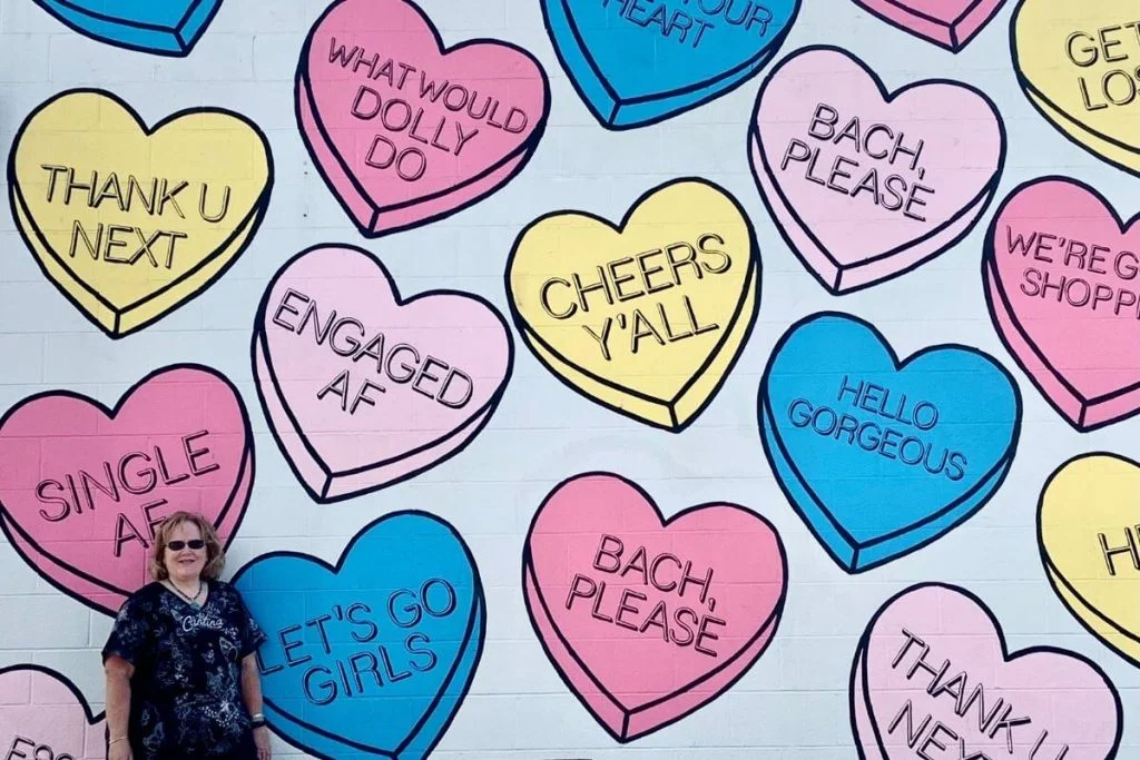 woman standing in front of a candy heart mural in Nashville