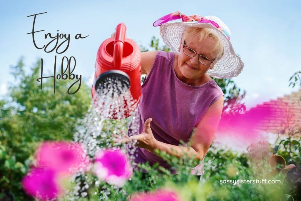 a middle aged woman waters her beautiful flower garden as one of her acts of self care