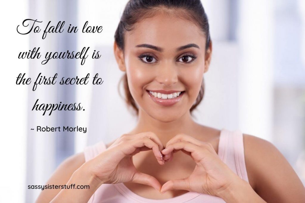 a beautiful happy woman making a heart shape with her hands promoting affirmations of self love