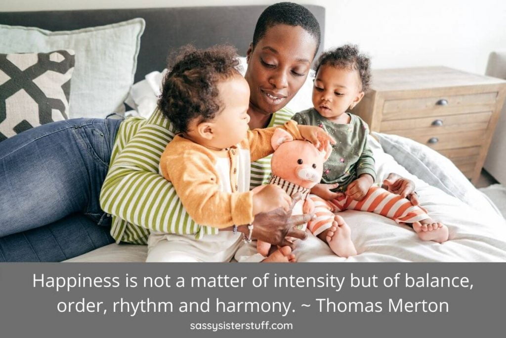a mom and two small children sit in bed together looking at each other lovingly and a quote about aspects of a balanced life