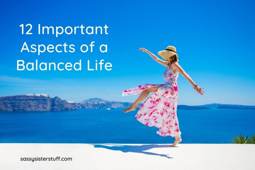 a woman in a pink and white floral dress dances along the edge of a body of water with cliffs in the background showing aspects of a balanced life