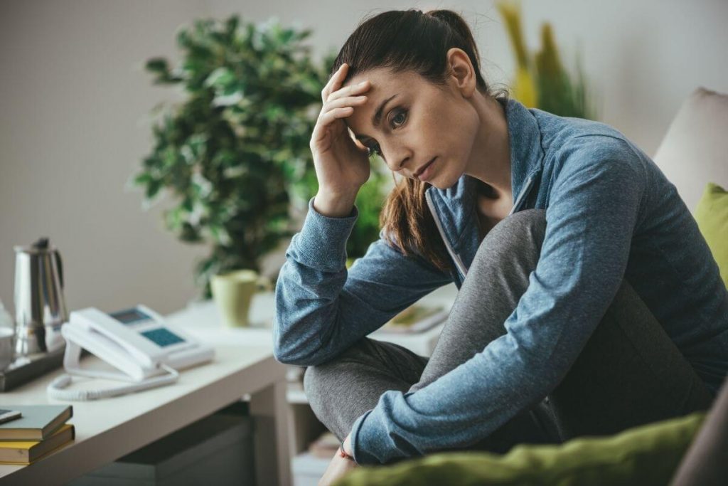 a young women sits at her deks with her hand holding her head and a worried look on her face because of struggles of life