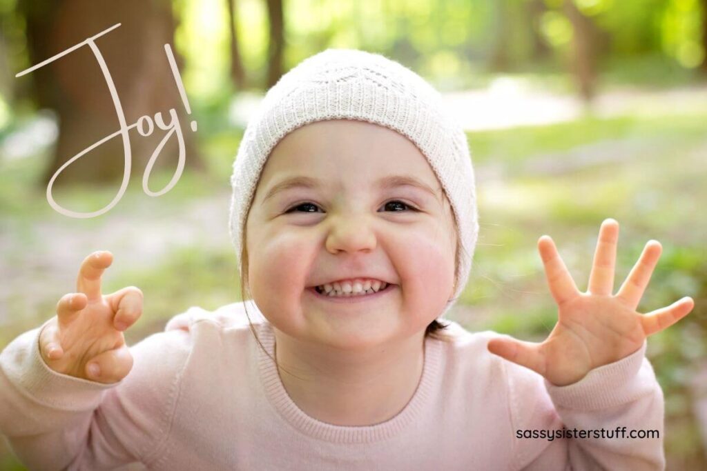 beautiful toddler wearing a pink beanie and sweatshirt smiling really big at the camera