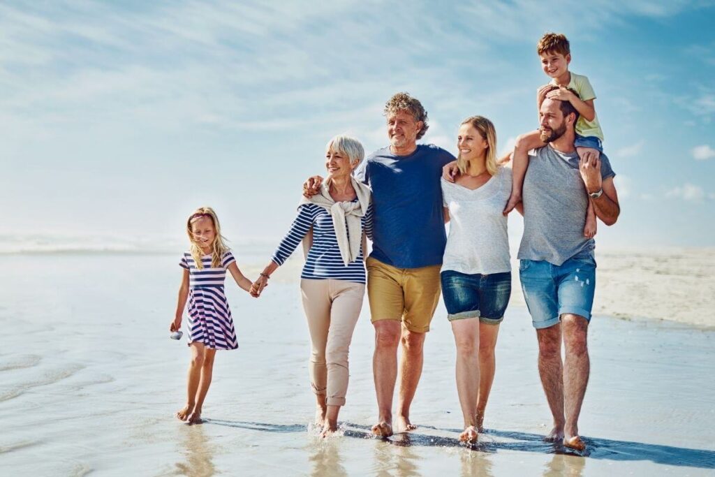 a multi-generational family with parents grandparents and kids walk along a beach showing how to live your best life