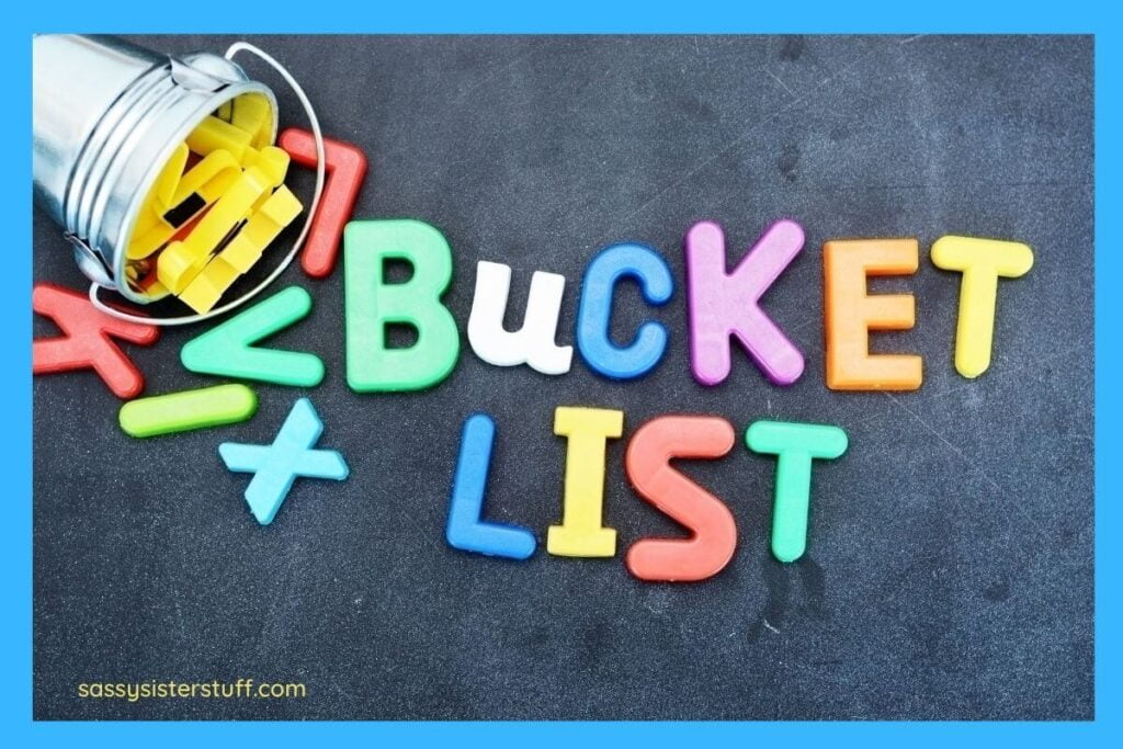 childrens magentic letters on a blackboard spell out bucket list in bright colors and a pale with extra letters lays nearby