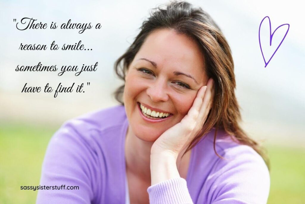 a beautiful woman sits outside on a sunny day wearing a lavender sweater smiling big at the camera plus a smile quote and a small purple heart in the corner