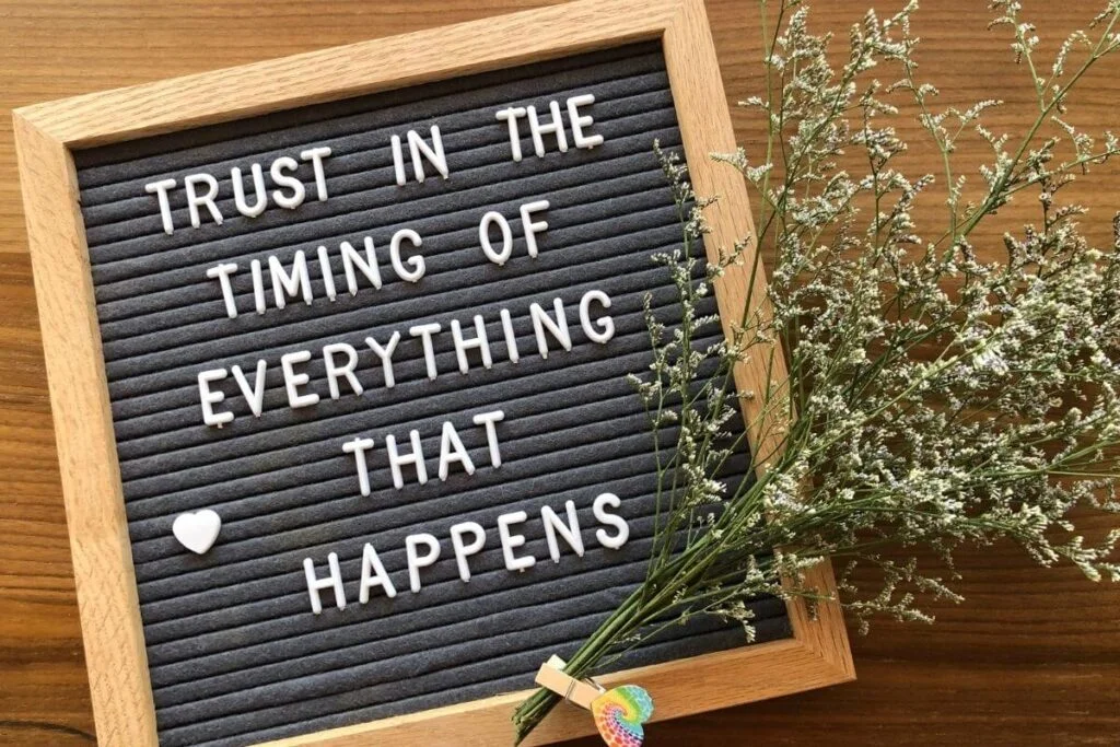 a black message board lays on a wooded desktop with trust the process quotes and greenery laying on the board