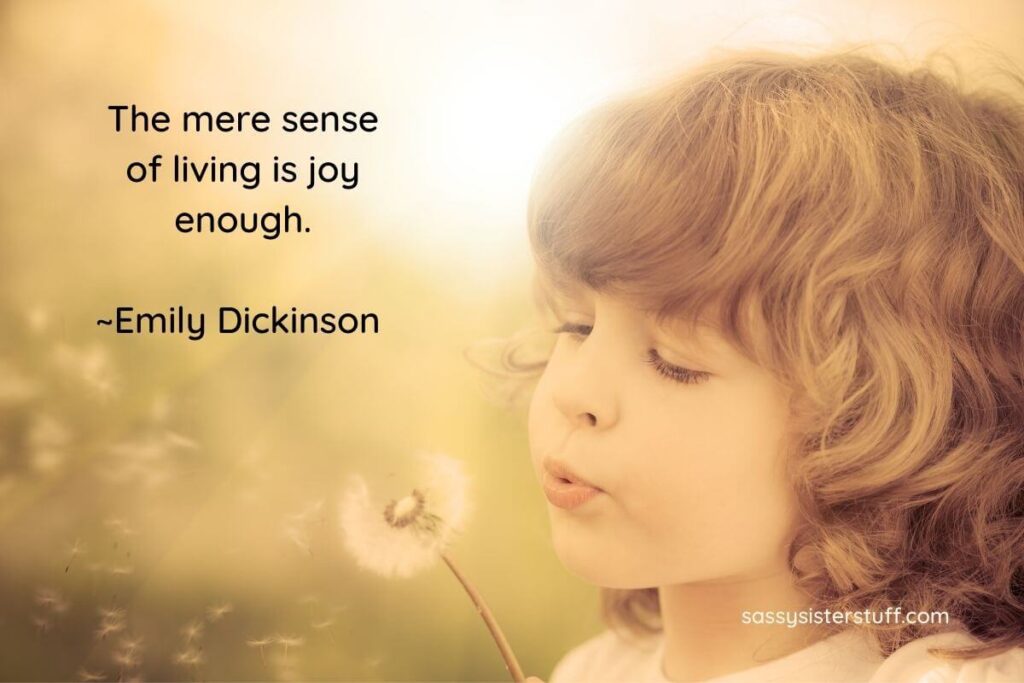 little girl blowing on a dandelion and a quote about joy from emily dickinson
