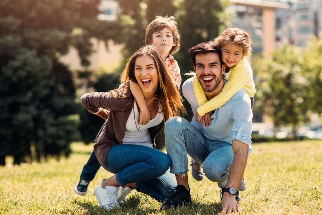 mom dad and two little children play together in the park