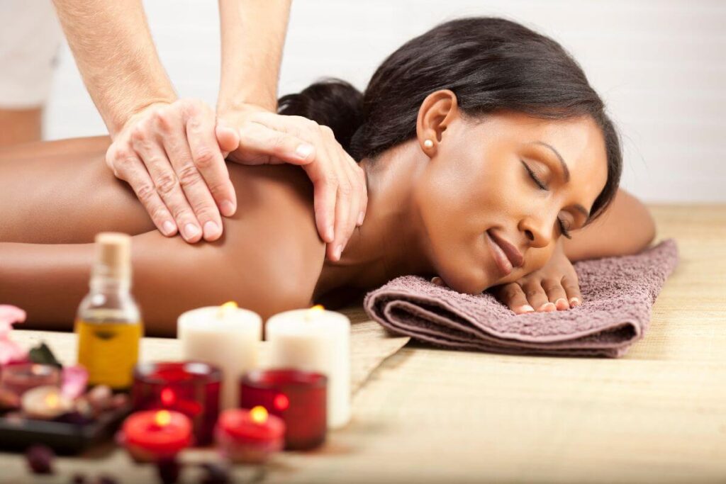 a young woman gets a massage in a relaxing and aromatic setting with candles and essential oils