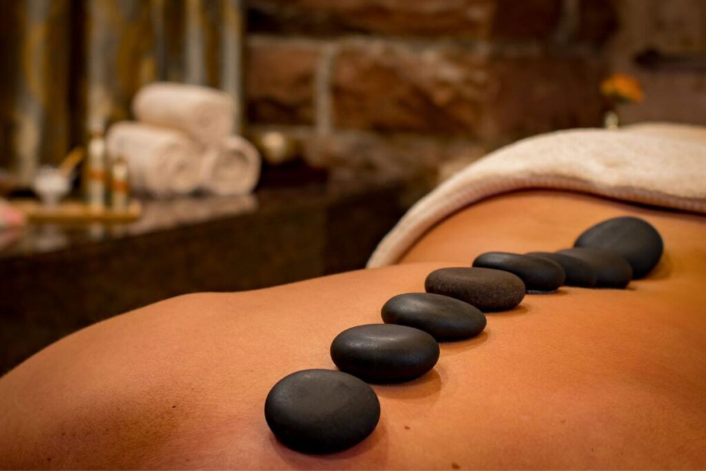 a top view of someones back with 8 hot stones laying down the middle in preparation for the best massage for stress and anxiety