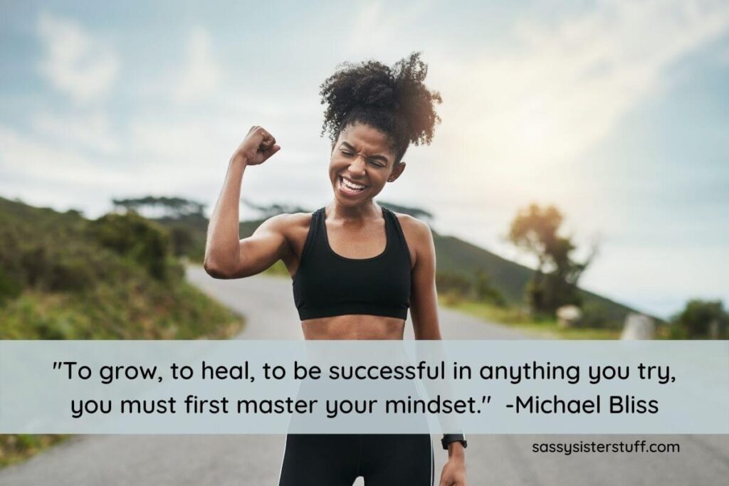 a young dark skinned enthusiastic woman holds her fist in the air to show mindset is everything