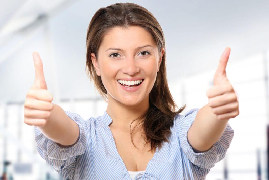 a young happy woman gives two thumbs up after reading her monday affirmations for positivity
