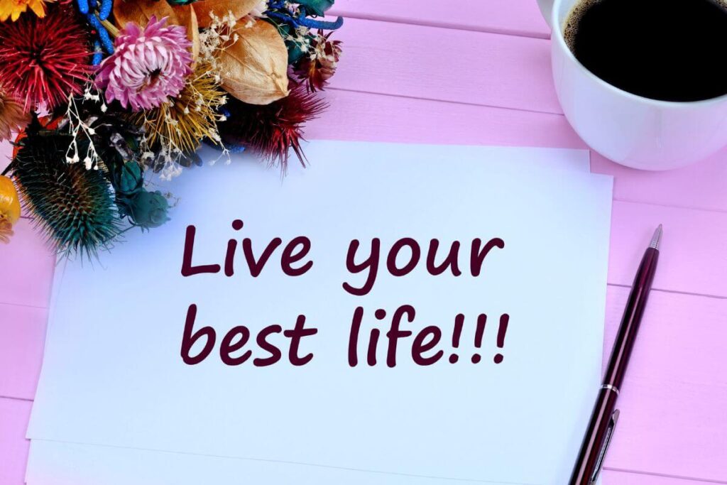 top view of flowers and coffee sitting on a lavender wooden table with a note that says live your best life!!!