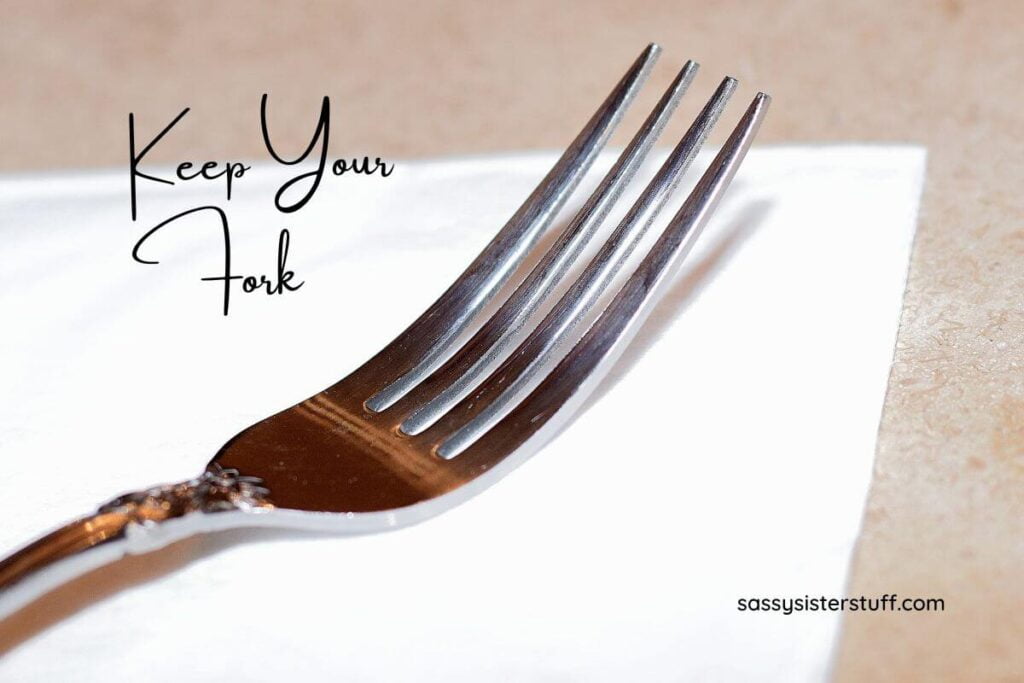 a close up of a silver fork sitting on a white napkin and text that says keep your fork