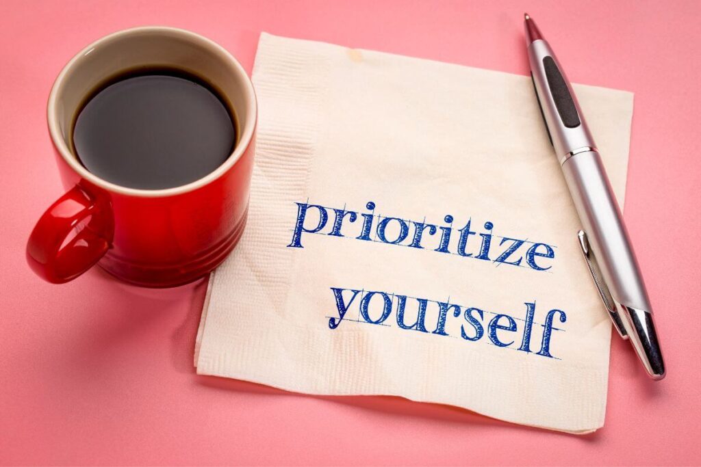 top view of a mug of coffee a pen and a napkin that says prioritize yourself