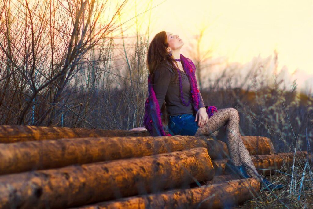a young woman in unique clothes sits outside and looks confidently up at the sky