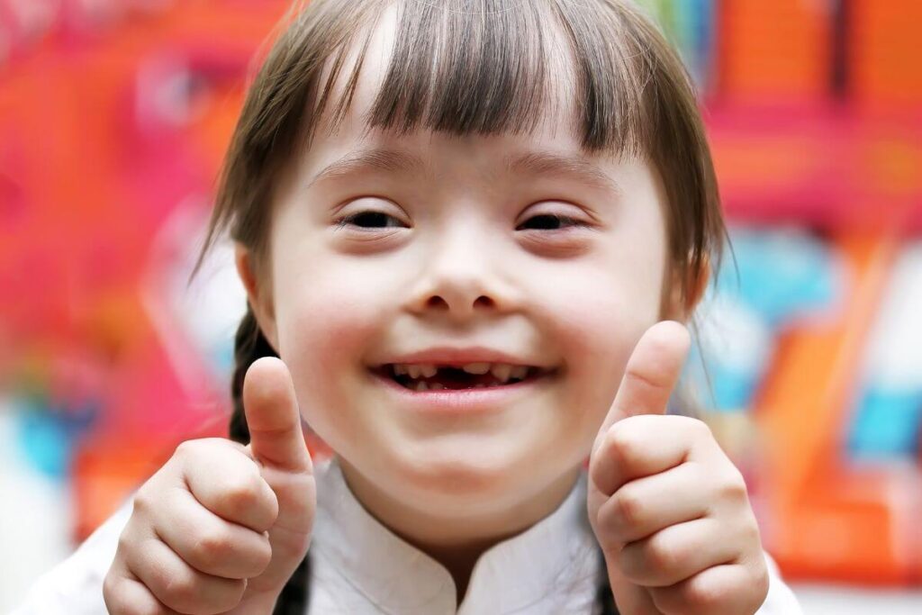 a little girl with down syndrome gives a thumbs up to show that she is confident and happy because her parents have said things all kids need to hear to teacher her acceptance and love