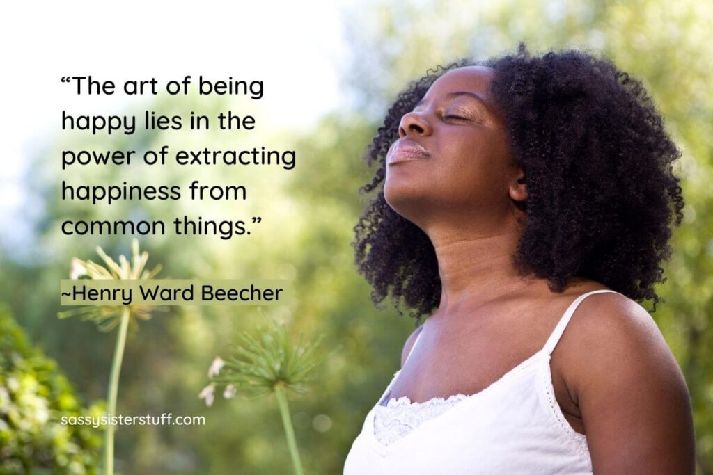 a dark skinned woman stands in a park with her eyes closed and smells the fresh air as she thinks about how we should be content with what life gives us plus a quote about happiness