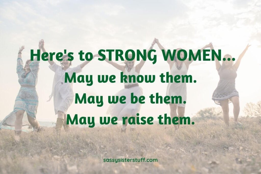 five happy women walk across a field with their hands connected in the air as they celebrate the hard working woman