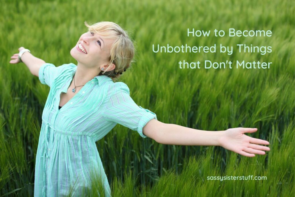 a beautiful women stands in a field of tall green grasses and smiles up into the sky because she is learning how to become unbothered by the stress of life