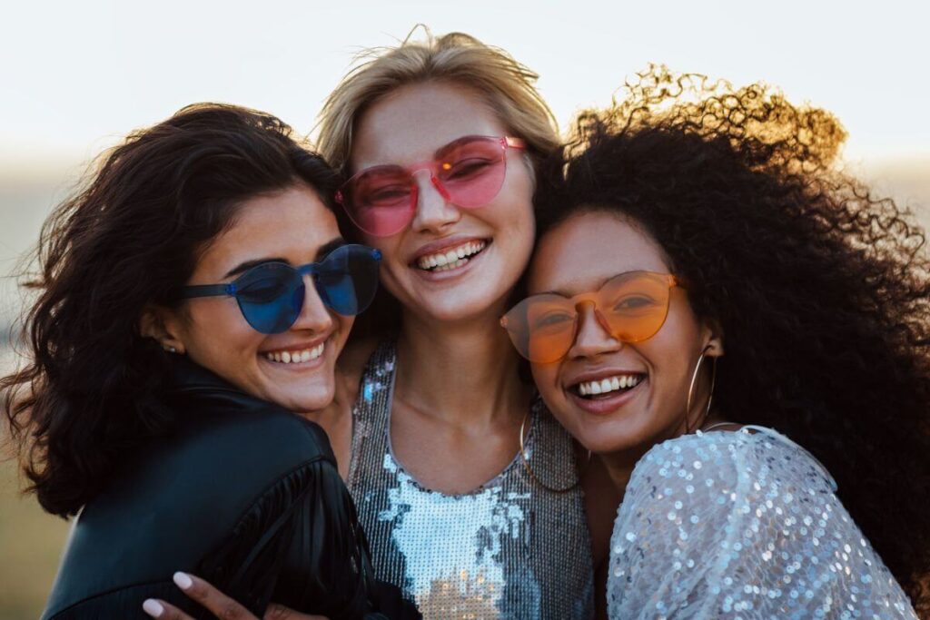 three young ladies hug with great big smiles after sharing self care reminders about wonderful friendships and social relationships