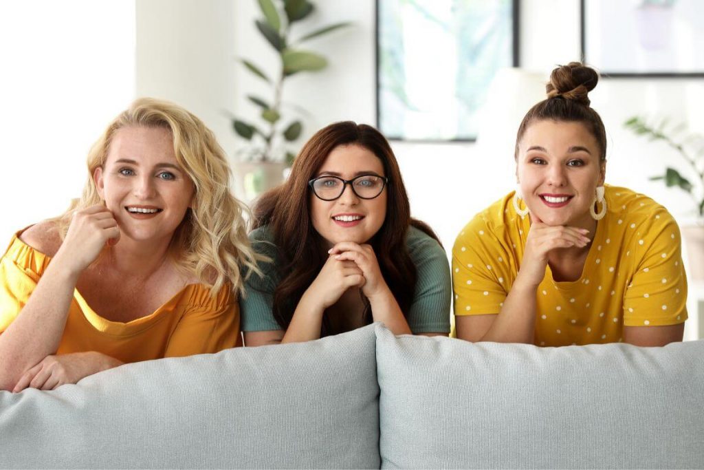 three happy women smile at the camera because they feel very comfortable in their bodies