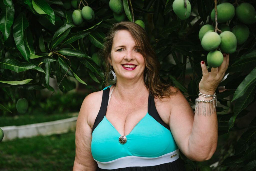 a confident middle aged woman poses outside under a pear tree