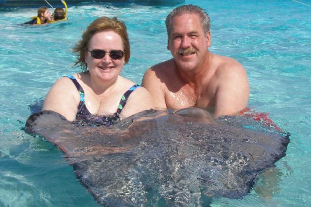 a middle aged couple swims in the crystal blue water with stingrays