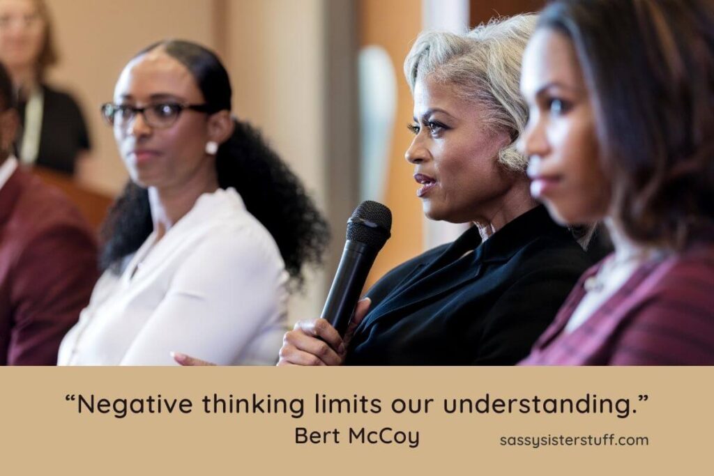 three black business women sit together confidently at a meeting without any negative thoughts