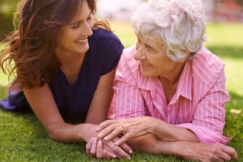 a woman and her mom lay in the grass on a sunny day talking about how important it is to die with memories not dreams