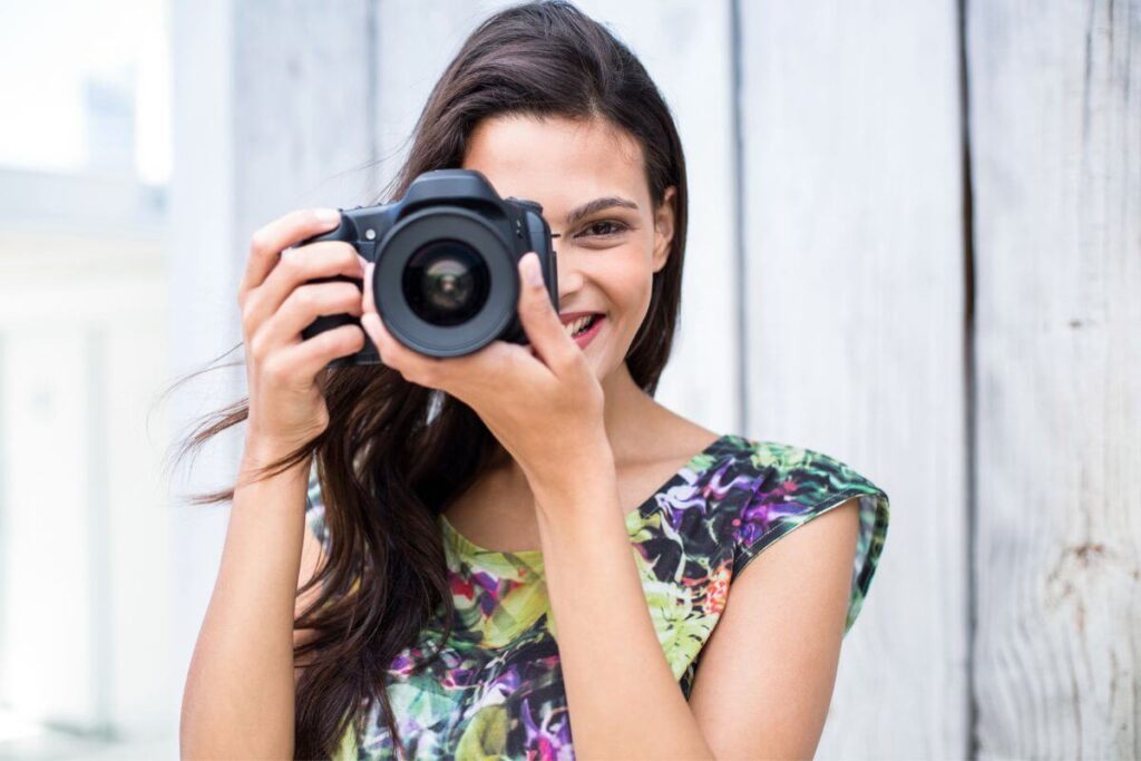 a young woman enthusiastically demonstrates how to use a dslr camera