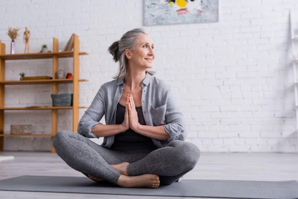 a middle aged woman does yoga on a mat in her home