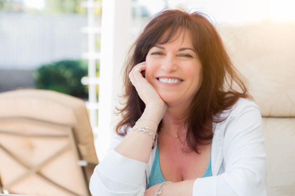 happy peaceful middle aged woman smiles at the camera because she has learned about many things to release for peace of mind and changed her life
