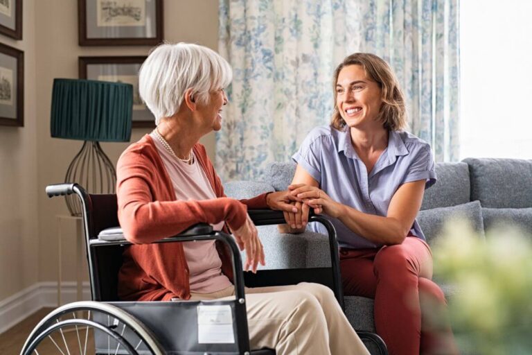 an adult child sits with her mom at home after figuring out what to do when elderly parent can't walk and gets her a wheelchair for improved mobility